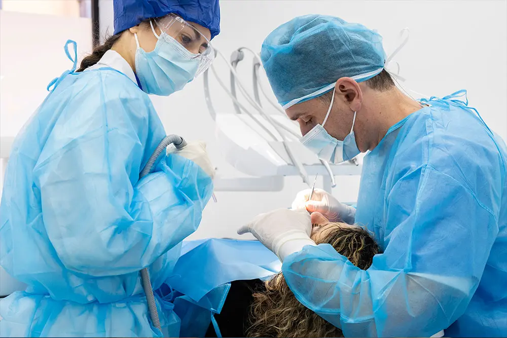 Une clinicienne et un chirurgien penchés sur le patient pendant l’intervention