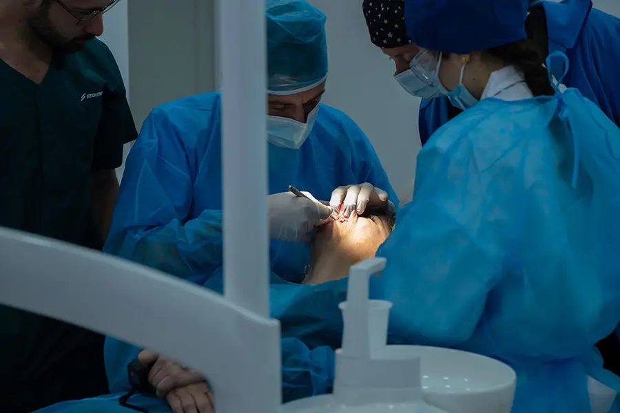 Deux cliniciens opérant, vus par-dessus le fauteuil