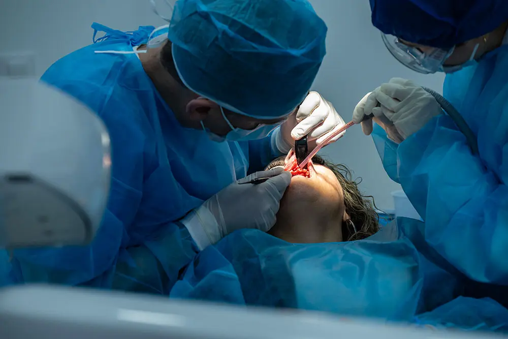 Deux paires de mains gantées opérant dans la bouche, vues de près